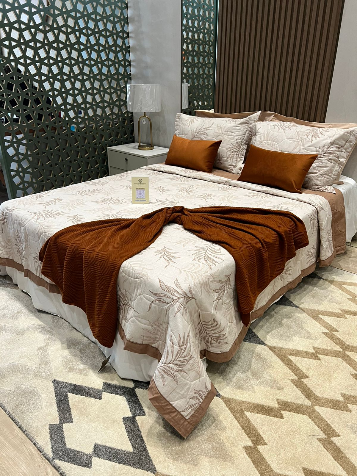 Cama montada em tons terrosos com manta e almofadas